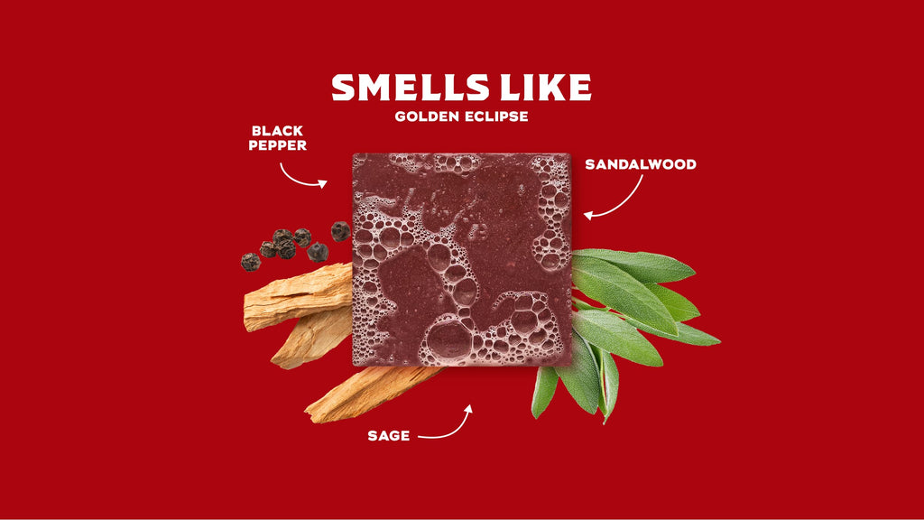 Soap bar surrounded by black pepper peppercorns, sandalwood leaves, and sage sprigs on red background.