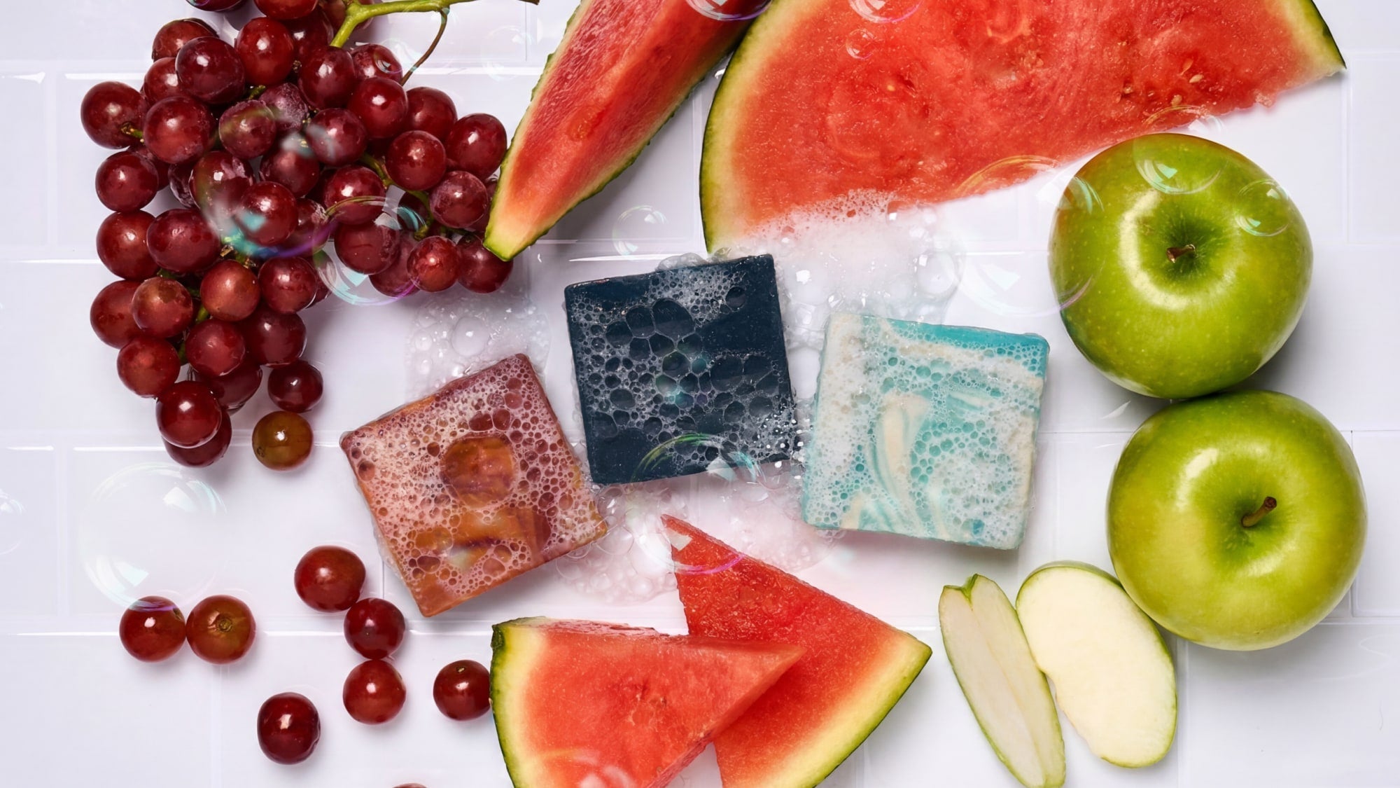 3 mini kids soaps in middle of watermelon, grapes and apples